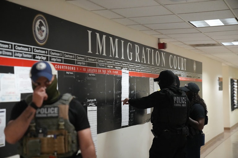 masked ICE agents look at lists of immigrants they plan on arresting at court