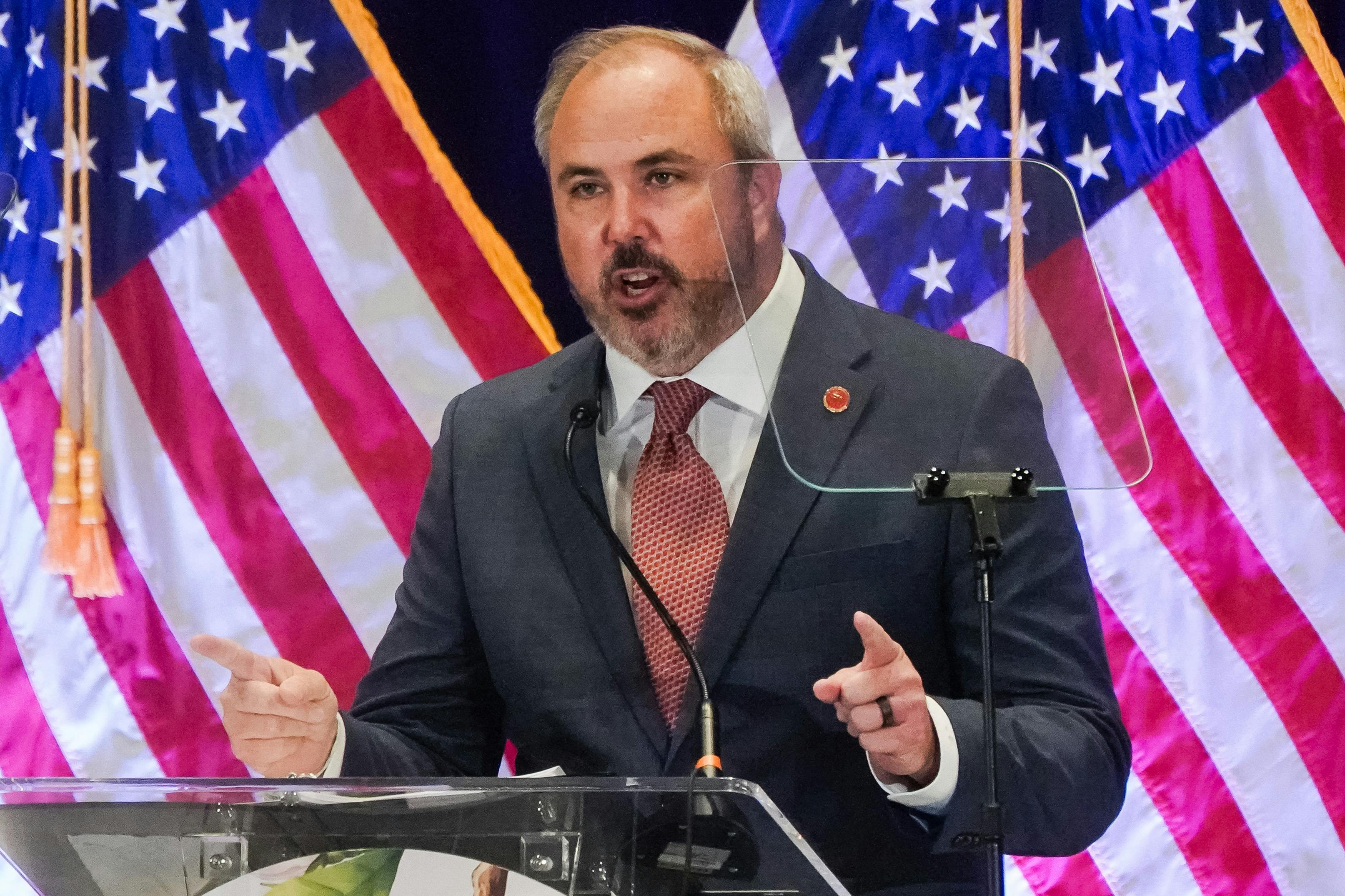 RNC Chair Joe Gruters speaks at a lectern in front of U.S. flags.