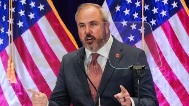 RNC Chair Joe Gruters speaks at a lectern in front of U.S. flags.