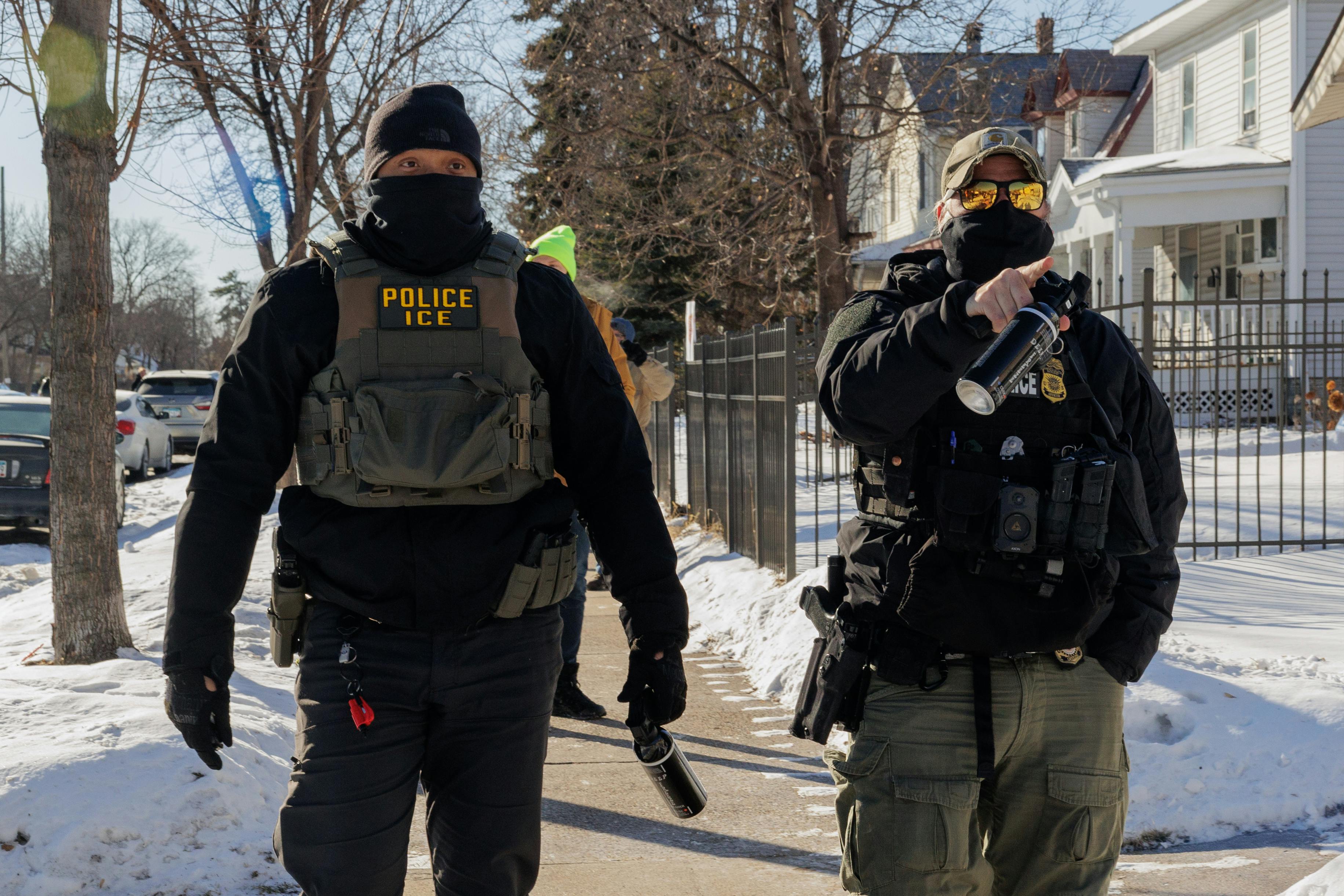 Two masked ICE agents walk outside.
