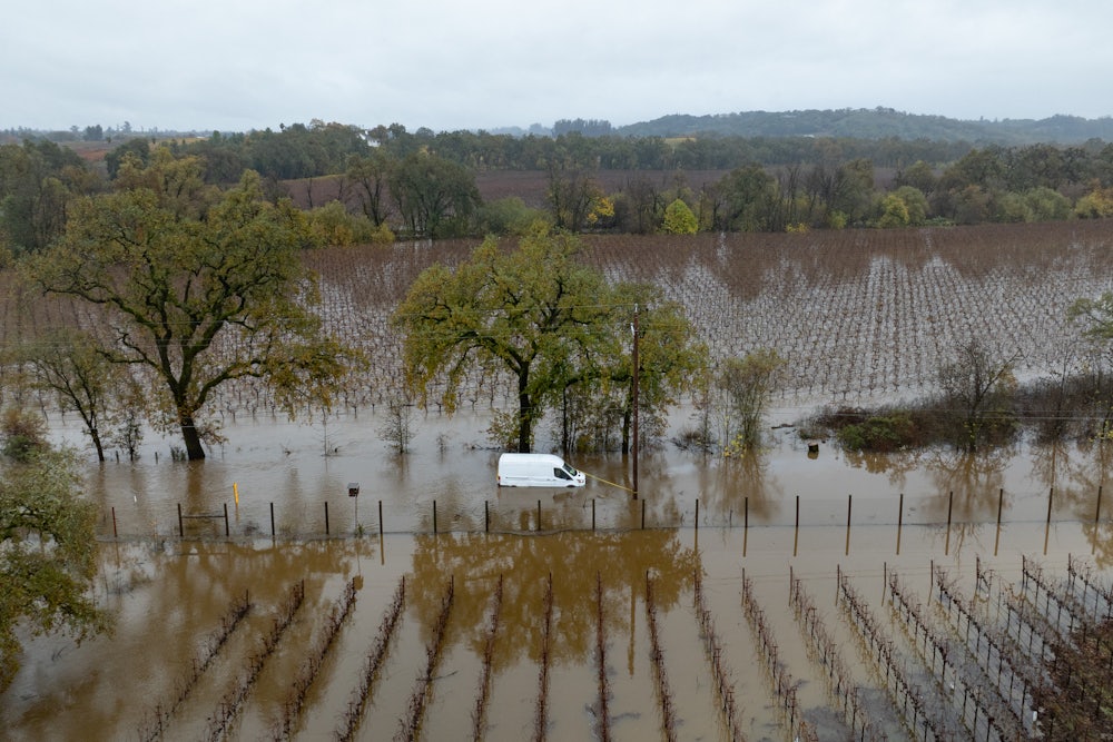 A flooded field with a white van stranded on a flooded road