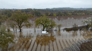 A flooded field with a white van stranded on a flooded road
