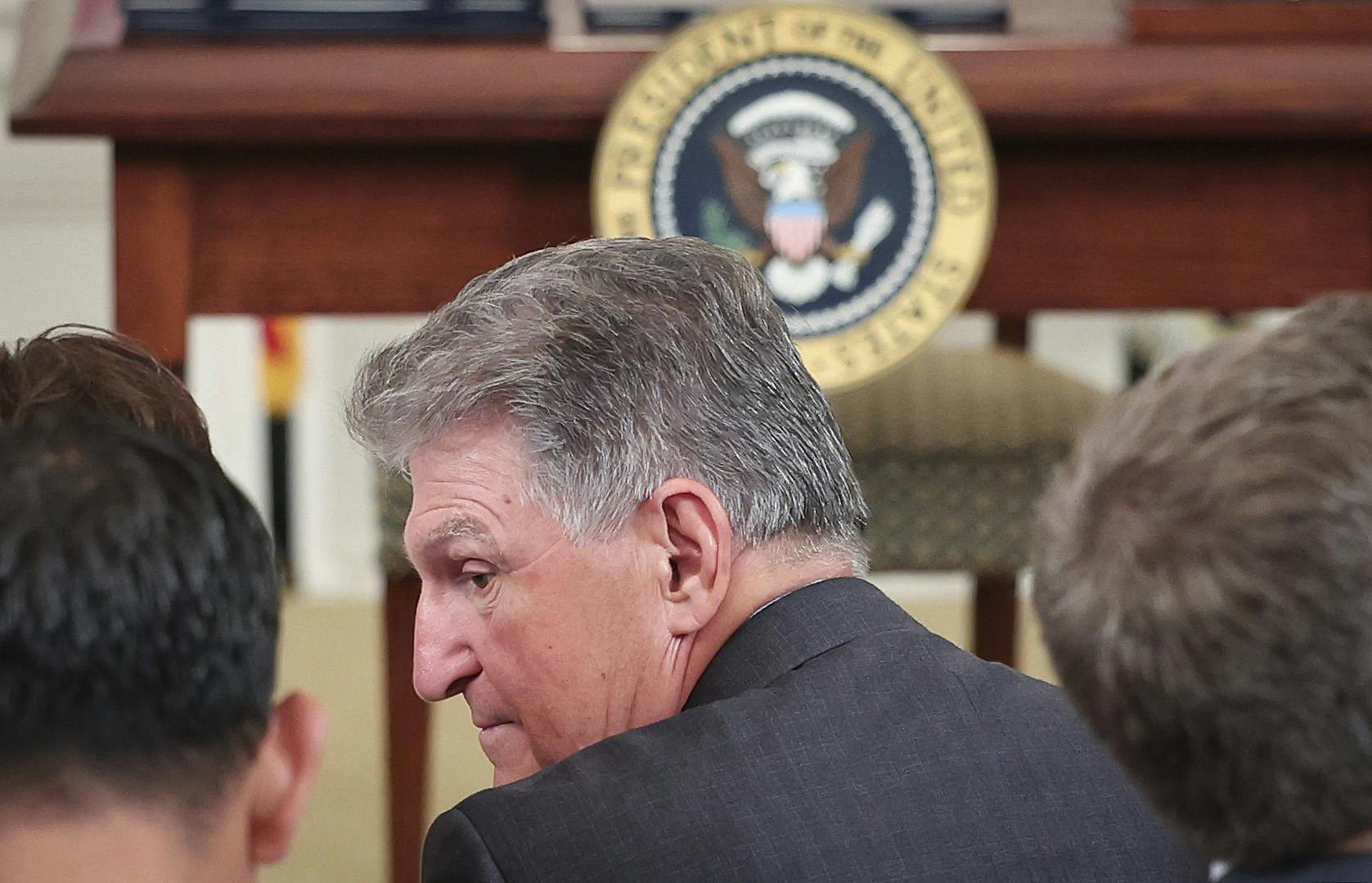 Senator Joe Manchin talks to others, facing away from the camera.