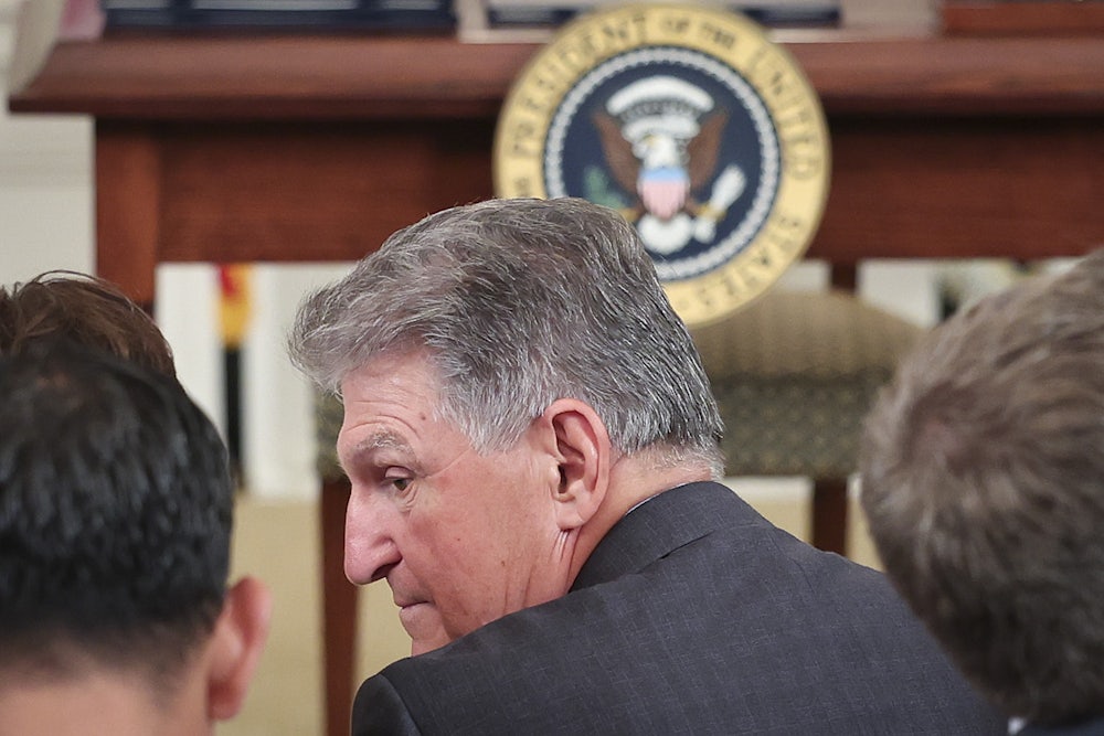 Senator Joe Manchin talks to others, facing away from the camera.