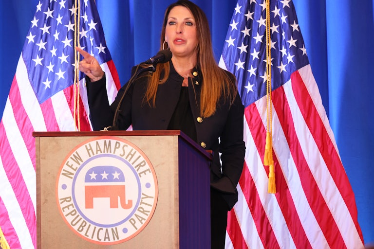 Ronna McDaniel speaks at a lecturn that says "New Hampshire Republican Party" with an elephant logo. U.S. flags and blue curtains are behind her.