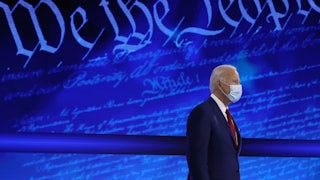 Joe Biden stands in front of a background reading “We the People.”