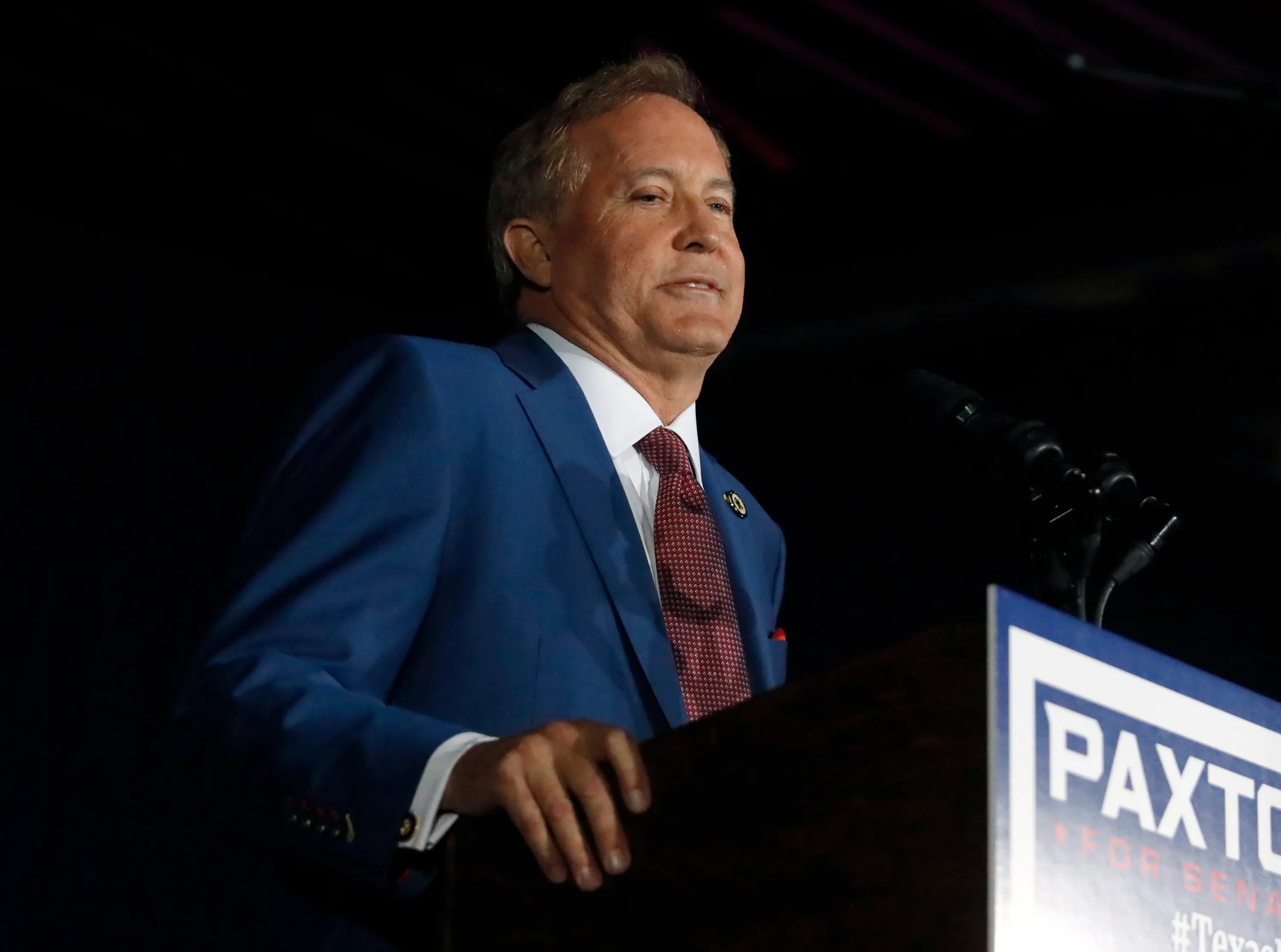Texas Attorney General Ken Paxton stands at a podium during a Senate campaign event.