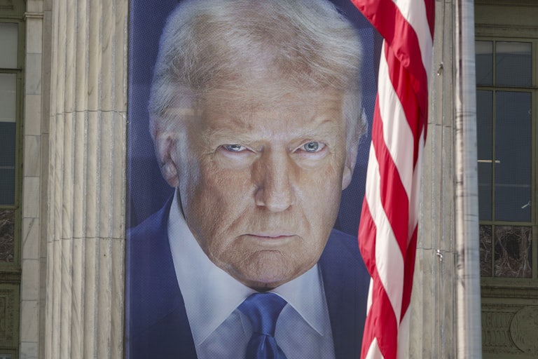 A giant banner of Donald Trump staring as a limp U.S. flag hangs in front of him.