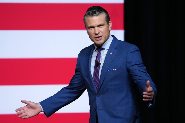 Pete Hegseth walks and spreads his arms as he speaks to military leaders (not pictured).