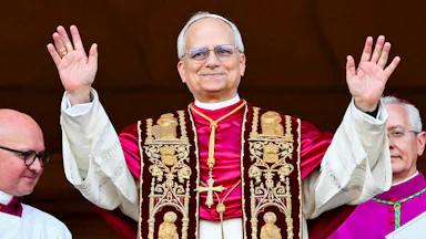 Pope Leo holds up both hands