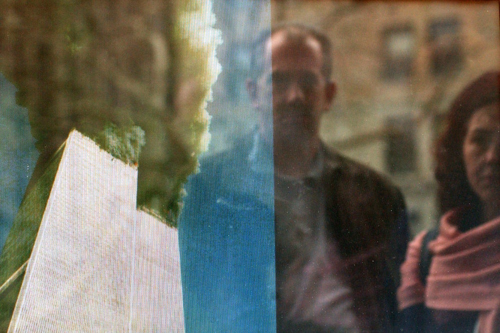 People watching a television replay scenes from the September 11, 2001 attack on the World Trade Center, reflected in the window of a store, February 20, 2002 in New York City.