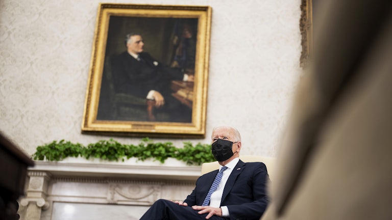 A masked President Joe Biden sits in the Oval Office.