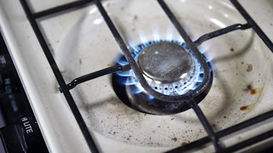 Image shows a lit gas burner, with food residue beneath.