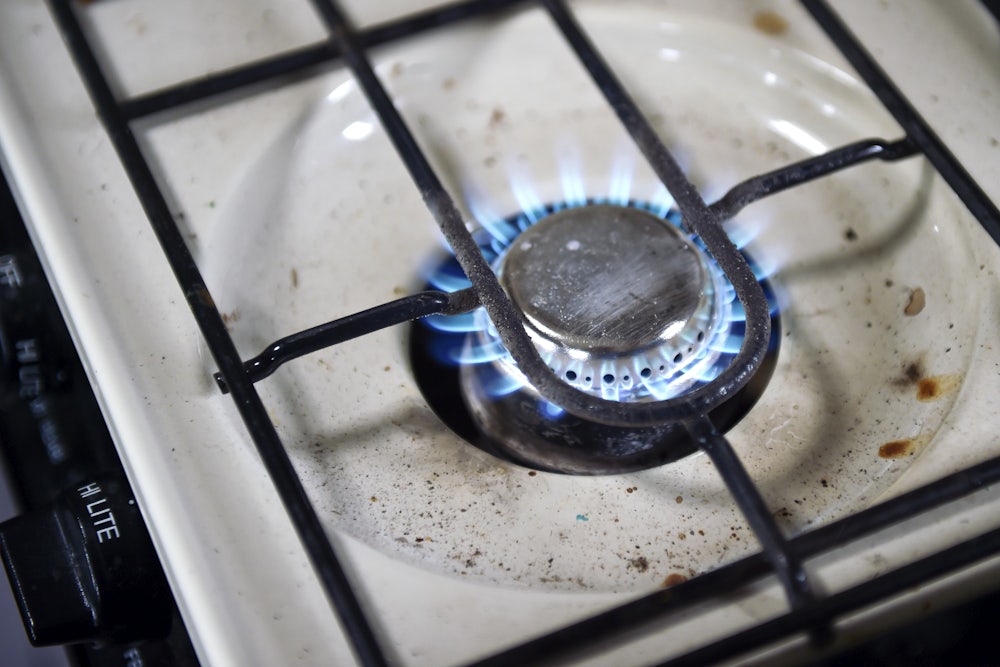 Image shows a lit gas burner, with food residue beneath.
