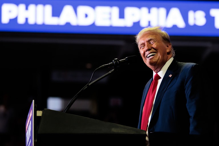 Donald Trump smiles as he stands at a podium