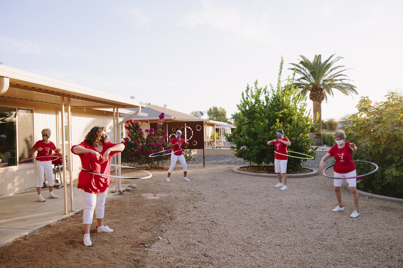 Five senior women hula hooping outdoors in a desert setting. 