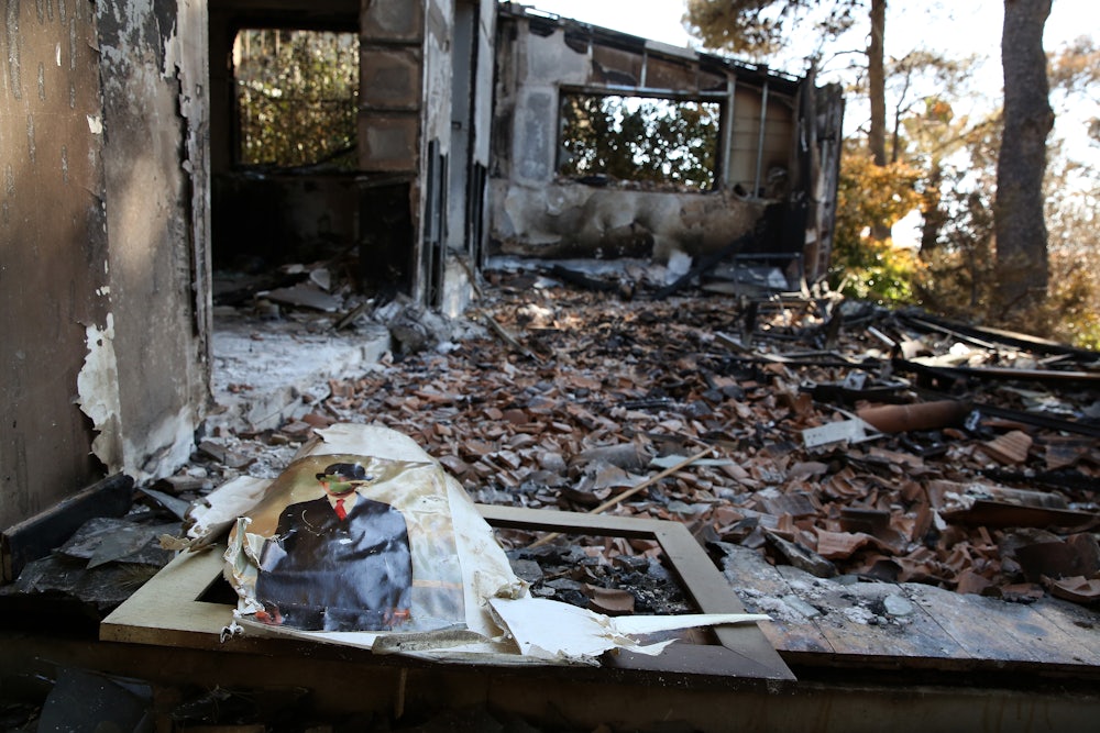 A print of the famous painting of a man with an apple in front of his face lies amid the ruins of a burned house.