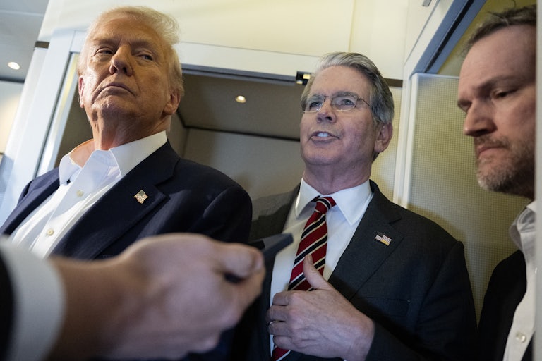 Treasury Secretary Scott Bessent speaks to reporters on Air Force One while standing between Donald Trump and Trade Representative Jamieson Greer
