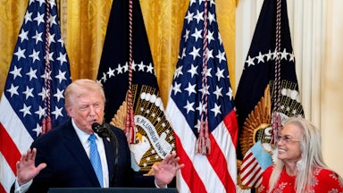 Donald Trump speaks into a mic while Miriam Adelson smiles and listens.