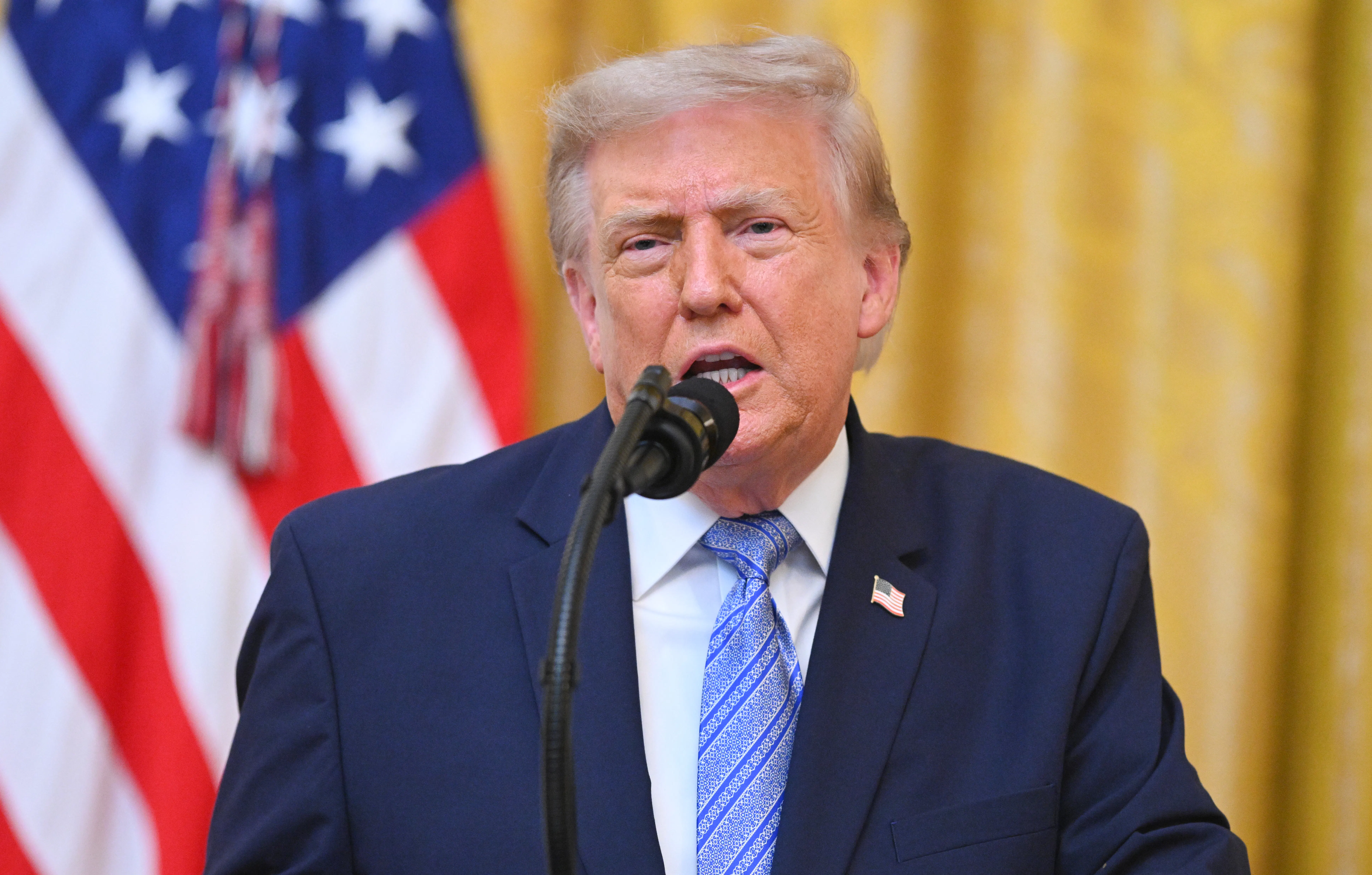 President Donald Trump speaks at the podium in the White House.