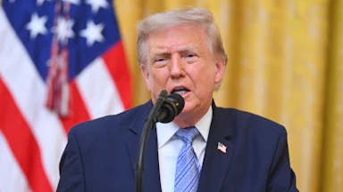 President Donald Trump speaks at the podium in the White House.