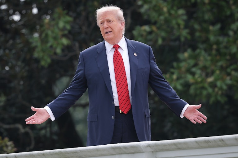 Donald Trump holds his arms out to the side and speaks while standing on the White House roof