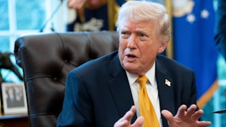 Donald Trump gestures and speaks while sitting at his desk in the Oval Office