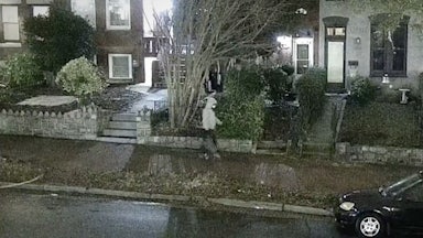 Jan. 6 suspect wears a gray hoodie and a face mask and walks in the streets of Washington, D.C. carrying a bag.