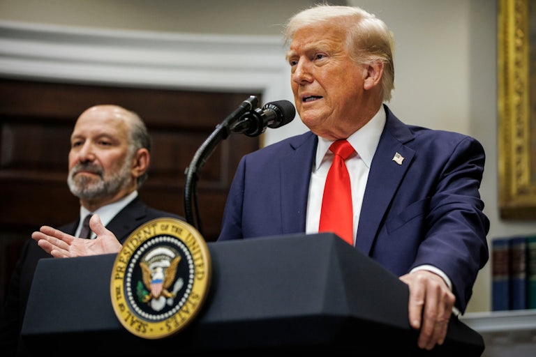 Donald Trump speaks at the presidential podium in the White House while Commerce Secretary Howard Lutnick stands beside him.