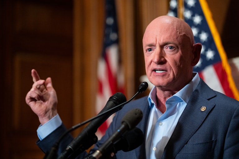 Senator Mark Kelly gestures while speaking at a podium
