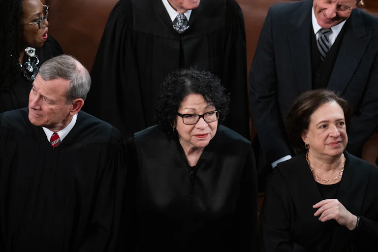 Sonia Sotomayor stands in the middle of Elena Kagan, right, and John Roberts. All are wearing black.