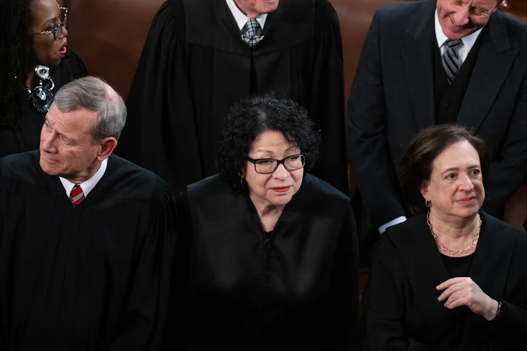 Sonia Sotomayor stands in the middle of Elena Kagan, right, and John Roberts. All are wearing black.