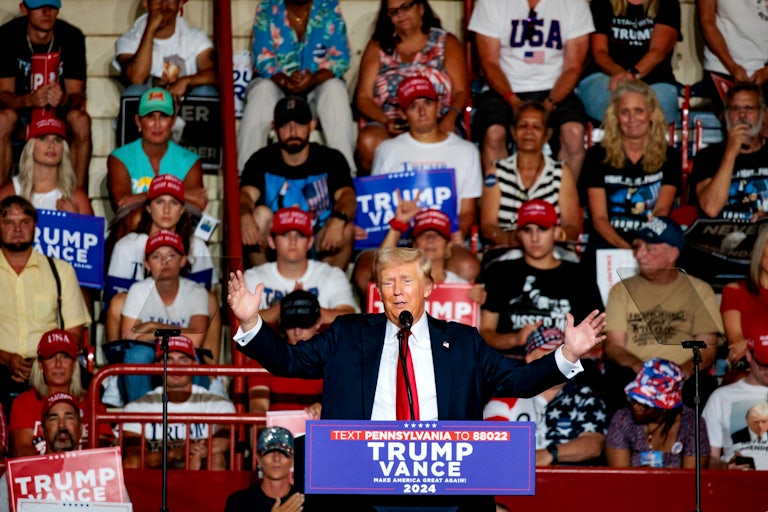Donald Trump holds his arms out as he speaks at a campaign rally