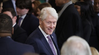 Former President Bill Clinton smiles and speaks while standing at a memorial service
