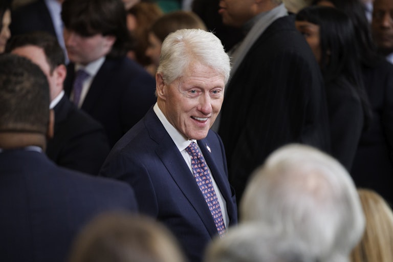 Former President Bill Clinton smiles and speaks while standing at a memorial service