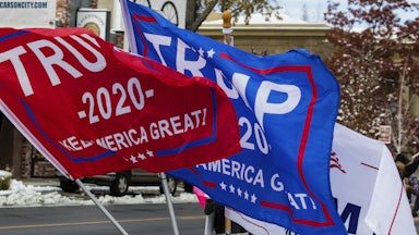 Flags that read "Trump 2020" fly over a street.