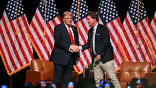 Donald Trump and Tucker Carlson shake hands on stage
