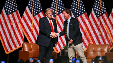 Donald Trump and Tucker Carlson shake hands on stage