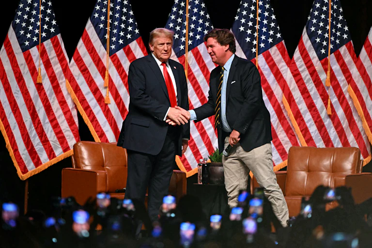 Donald Trump and Tucker Carlson shake hands on stage