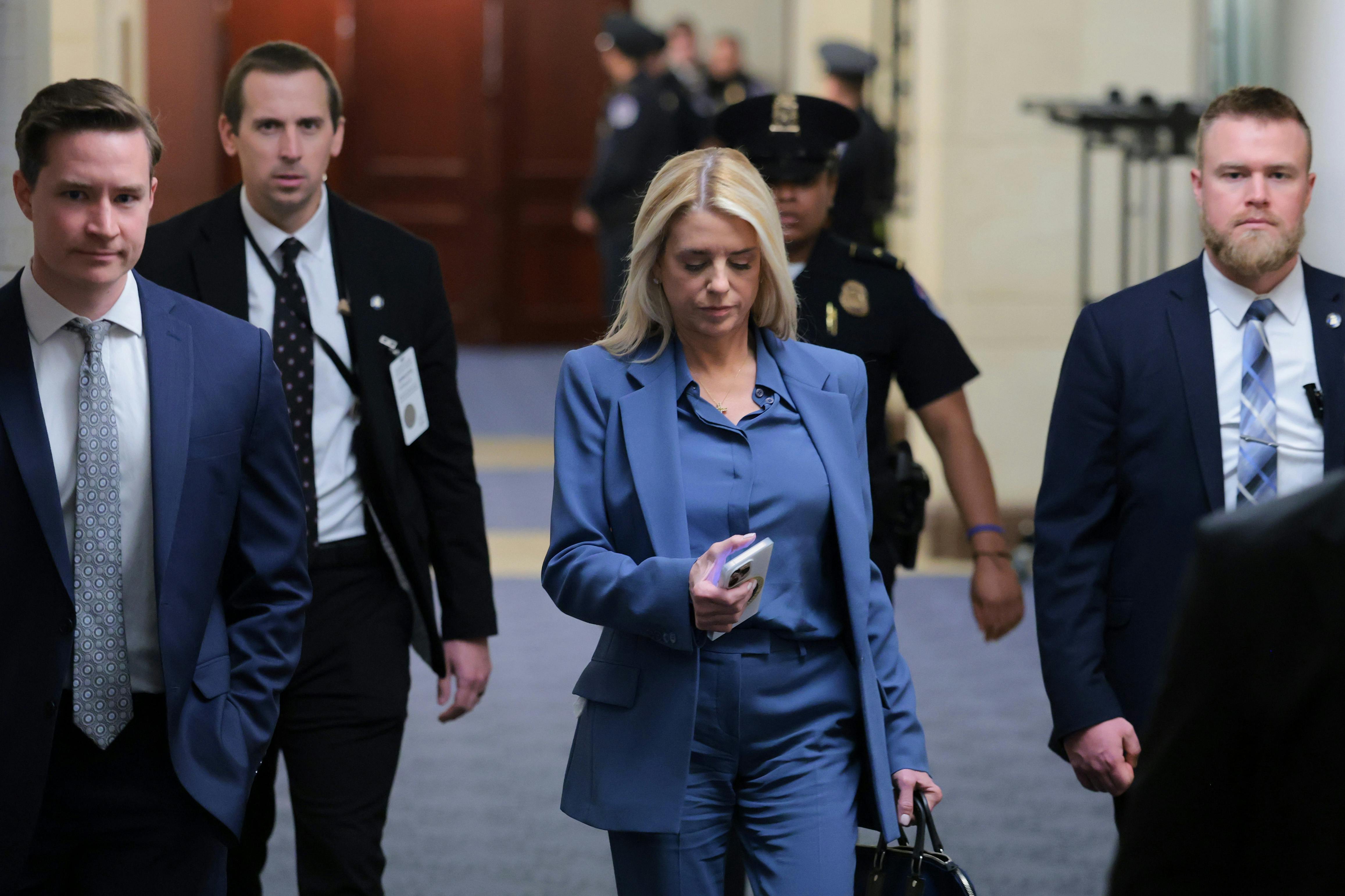 Attorney General Pam Bondi walks through Capitol Hill along with three men and a police officer.