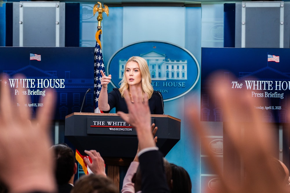 Karoline Leavitt points as hands are raised in front of her.