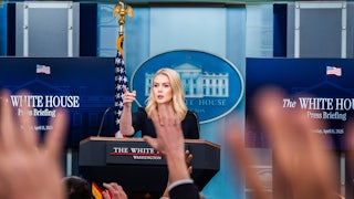 Karoline Leavitt points as hands are raised in front of her.