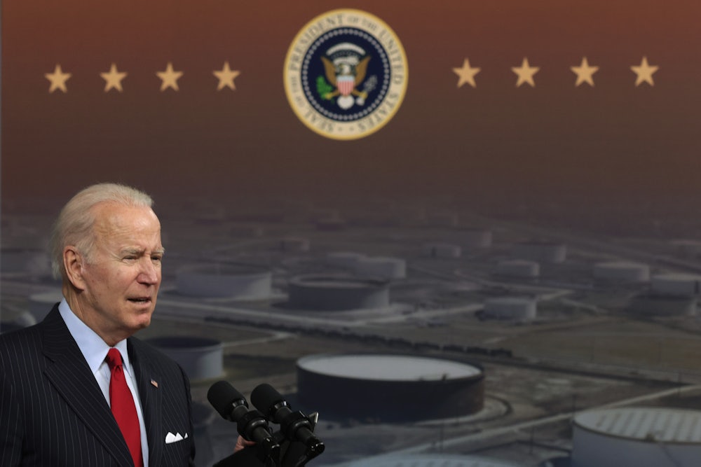 President Biden speaks in front of a backdrop depicting industrial storage tanks.