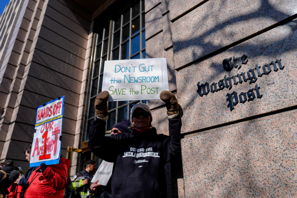 A demonstrator holds a “Don’t Gut the Newsroom Save the Post” sign alongside members of The Washington Post guild and supporters during a “Save The Post” rally outside The Washington Post headquarters in Washington, D.C.