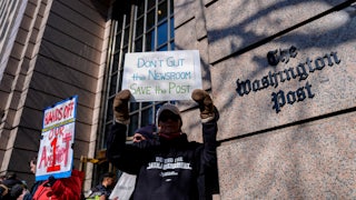 A demonstrator holds a “Don’t Gut the Newsroom Save the Post” sign alongside members of The Washington Post guild and supporters during a “Save The Post” rally outside The Washington Post headquarters in Washington, D.C.