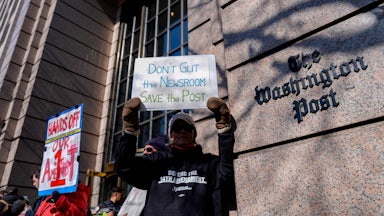 A demonstrator holds a “Don’t Gut the Newsroom Save the Post” sign alongside members of The Washington Post guild and supporters during a “Save The Post” rally outside The Washington Post headquarters in Washington, D.C.