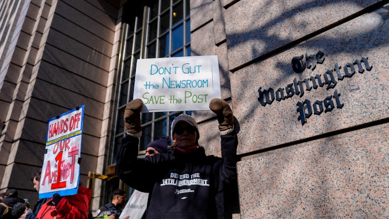A demonstrator holds a “Don’t Gut the Newsroom Save the Post” sign alongside members of The Washington Post guild and supporters during a “Save The Post” rally outside The Washington Post headquarters in Washington, D.C.