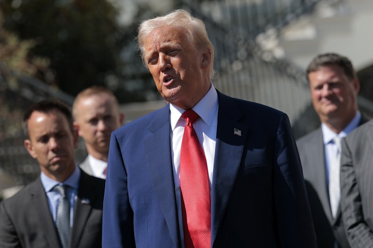 Donald Trump speaks outside the White House as several man stand behind him.
