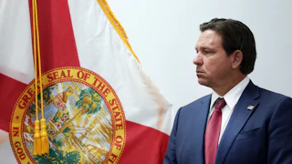 Ron DeSantis stands in front of the Florida state flag