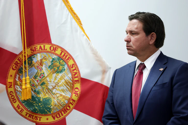 Ron DeSantis stands in front of the Florida state flag